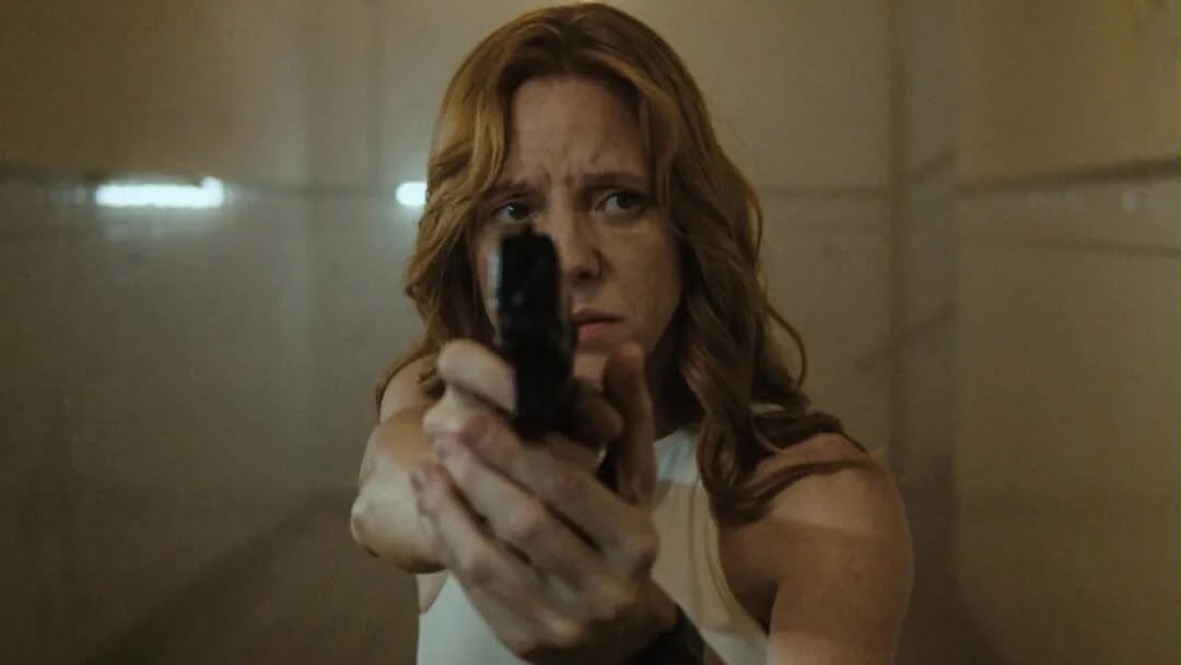 Mulher segura uma arma apontada para a câmera em cena do filme O Ar que a Gente Respira.